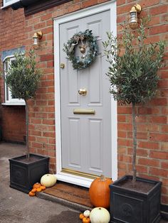 the front door is decorated with pumpkins and greenery