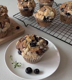 muffins with blueberries on a plate next to some cooling racks and a cutting board