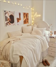 a bedroom with white bedding and pictures on the wall