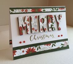 a christmas card with the word merry written in wooden letters and poinsettis