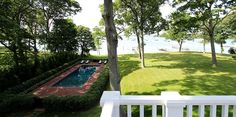 an aerial view of a lawn with a pool in the middle and trees surrounding it