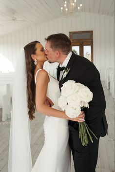 a bride and groom kissing in front of a chandelier