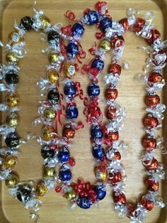 an assortment of candy candies on a wooden tray with bows and ribbons around them