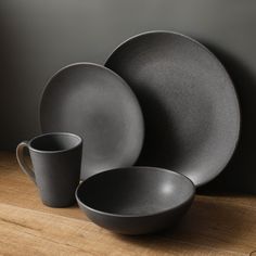 black dinnerware set on wooden table with dark background