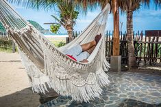 a man laying in a hammock on the beach