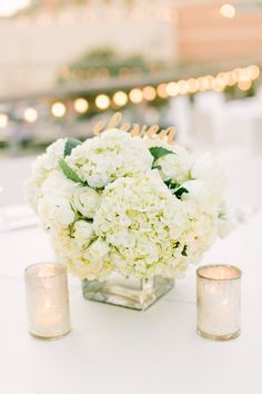 white flowers and candles are sitting on a table