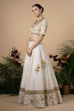 Ivory lehenga with embroidered waistband and floral embroidered hemline. Comes with blouse and dupatta. Component: 3 Pattern: Embroidery Type Of Work: Zardozi, beads and Sequin Neckline: Round Sleeve Type: Half Fabric: Dupatta: Cotton Silk, Lining: Shantoon Color: White Other Details:  Cutwork sleeve hems Dupatta with embellished border Low back with tie up back Closure: Blouse: Hook back; Lehenga: Side zip and tie up Occasion: Wedding - Aza Fashions Cream Embellished Anarkali Set, Fitted Floor-length Sets With Embroidered Border, Festive Off White Embellished Sets, Festive Embellished Off White Sets, Festive Off-white Embellished Sets, Fitted Floor-length Lehenga With Embroidered Border, Bollywood Style Dress With Embroidered Border For Reception, Cream Bollywood Lehenga With Floral Embroidery, Floor-length Lehenga With Embroidered Border