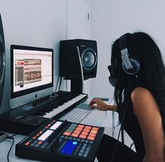 a woman sitting in front of a computer with headphones on and music equipment around her