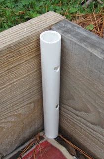 a white pipe sticking out of the ground next to a wooden fence