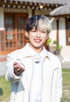 a young man in a white jacket pointing at the camera with his right hand out