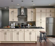 an image of a kitchen with white cabinets and black counter tops in the center is a bar stool