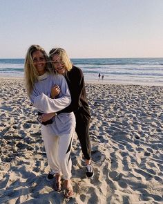 two women standing on the beach hugging each other