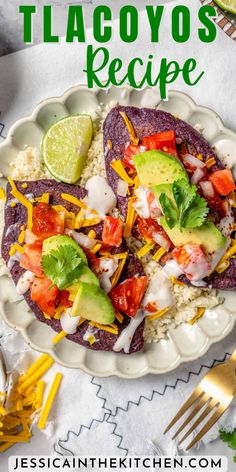 a white plate topped with two tacos covered in cheese and avocado next to a fork