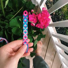 a person holding a pink and blue toothbrush in their hand next to some flowers