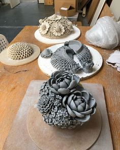 three clay flowers sitting on top of a wooden table