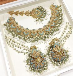 an elaborate necklace and earring set is displayed in a white box on a table