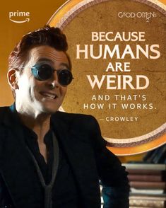 a man wearing sunglasses sitting in front of a sign that says because humans are weird and that's how it works