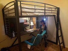 a woman sitting on top of a bunk bed next to a desk and computer monitor