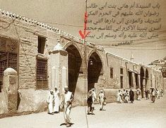 an old photo of people walking down the street in front of some buildings with writing on them