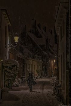 a person walking down a snowy street at night