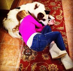 a woman laying on the floor next to a white and brown dog with her head down