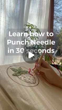 a woman is sitting in front of a window and writing on a piece of fabric with the words learn how to punch needle in 30 seconds