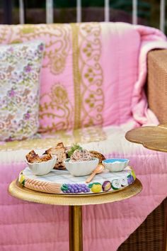 a table topped with bowls of food on top of a wooden table next to a pink couch