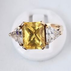 A quite pretty 9ct gold ring with a large square yellow cubic zirconia flanked by a pair of triangular white cubic zirconia, looks like yellow sapphire and diamond, all carefully mounted in a quite robust gold ring. Assayed and hallmarked as 9ct yellow gold in London Assay office in 1991. Size is "M.1/2" or US "6.1/2"; band width 2mm; head width 10mm; weight 4.4 gram. Cleaned and ready to wear from the box. Postage Paid Worldwide. Classic Yellow Diamond Ring With Accents, Yellow Emerald-cut Ring With Diamond Accents, Yellow Emerald Cut Rings With Diamond Accents, Yellow Emerald Cut Ring With Diamond Accents, Elegant Yellow Diamond Ring Hallmarked, Classic Gold Topaz Ring With Baguette Cut, Gold Cubic Zirconia Square Cut Rings, Yellow Topaz Emerald-cut Ring In Fine Jewelry, Yellow Emerald Cut Topaz Ring In Fine Jewelry Style