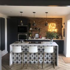 a kitchen with black and white tiles on the wall, bar stools in front of it