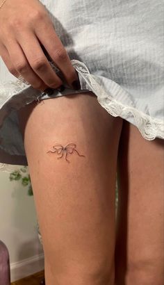 a woman's thigh with a small spider tattoo on the back of her leg