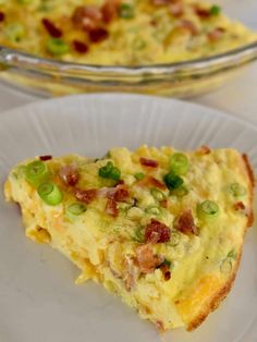 a slice of quiche on a white plate next to a glass casserole dish