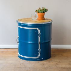 a potted plant sitting on top of a blue barrel with metal trimmings