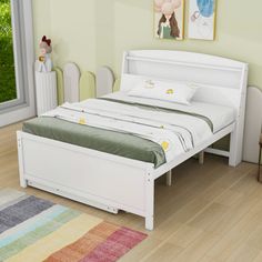 a white bed sitting on top of a hard wood floor next to a green wall