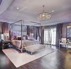 a bedroom with a canopy bed sitting on top of a hard wood floor next to a chandelier