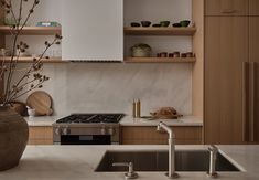 a kitchen with white marble counter tops and wooden cabinetry, along with a stainless steel sink