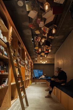 a man sitting on a bench in front of a bookshelf filled with books