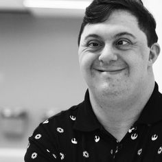 a black and white photo of a man smiling at the camera with his eyes wide open