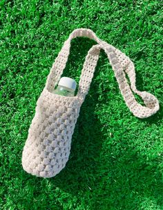 a crocheted water bottle bag laying on the grass