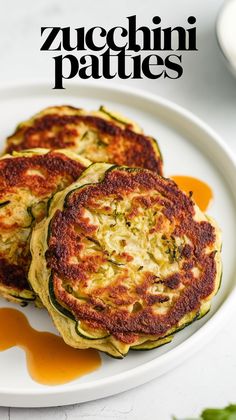 zucchini patties on a white plate with sauce drizzled around them