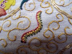 a close up view of some embroidery work on a piece of white fabric with gold thread