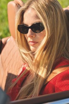 a woman wearing sunglasses sitting in the back of a car