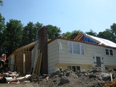 a house that is being built with rubble in the foreground and trees in the background