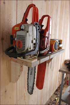 two chainsaws are sitting on a wooden shelf