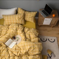 a bed covered in yellow and white checkered sheets with an open laptop on it