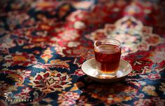 a cup of tea sitting on top of a saucer next to a colorful rug