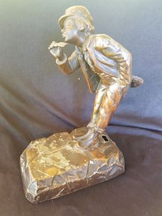 a bronze statue of a boy holding a baseball bat on a stone base with a black background