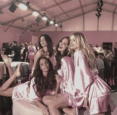 three women in pink robes posing for the camera at a fashion show with other people