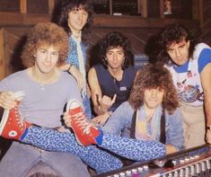 a group of young men sitting next to each other in front of a mixing desk