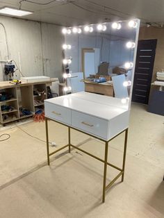 a dressing table with lights on it in the middle of a room filled with furniture