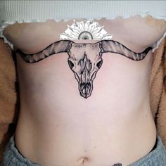 a woman with a cow skull tattoo on her stomach